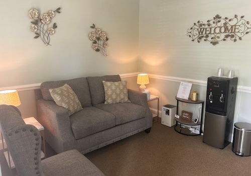 waiting area with couch and water cooler and art on the walls
