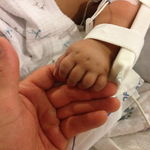 infant hand in a splint with IV holding adult hand