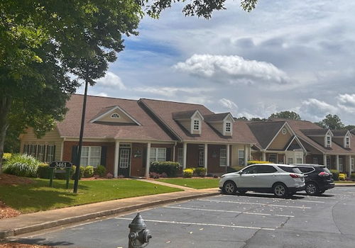 exterior of brick building with while columns and parking lot