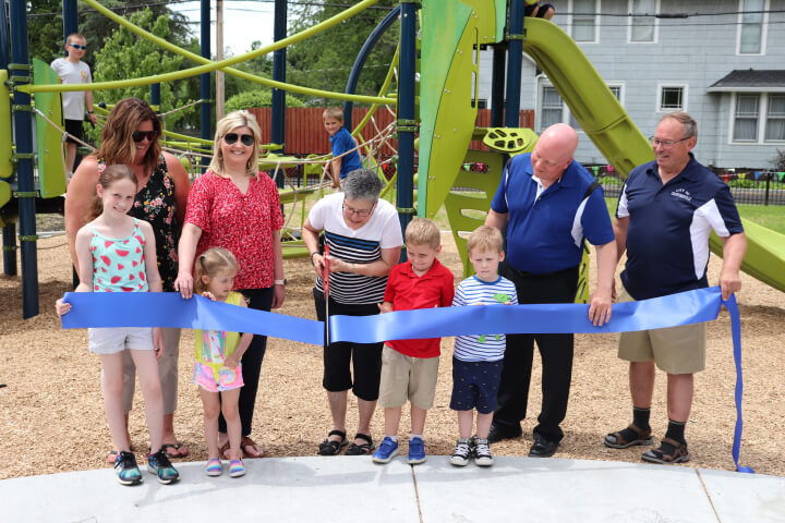 Community members and kids cutting the blue ribbon for park opening