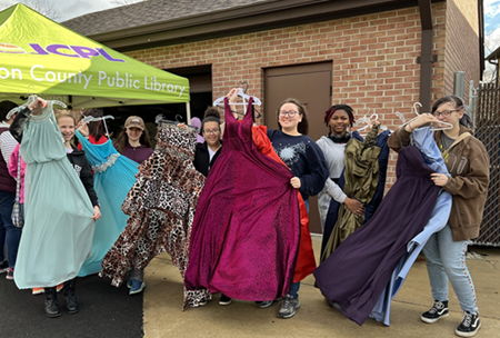 several teen girls holding up Project Prom dresses in front of the Franklin Branch barn