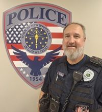Officer Jim Vahle in uniform in front of the police shield