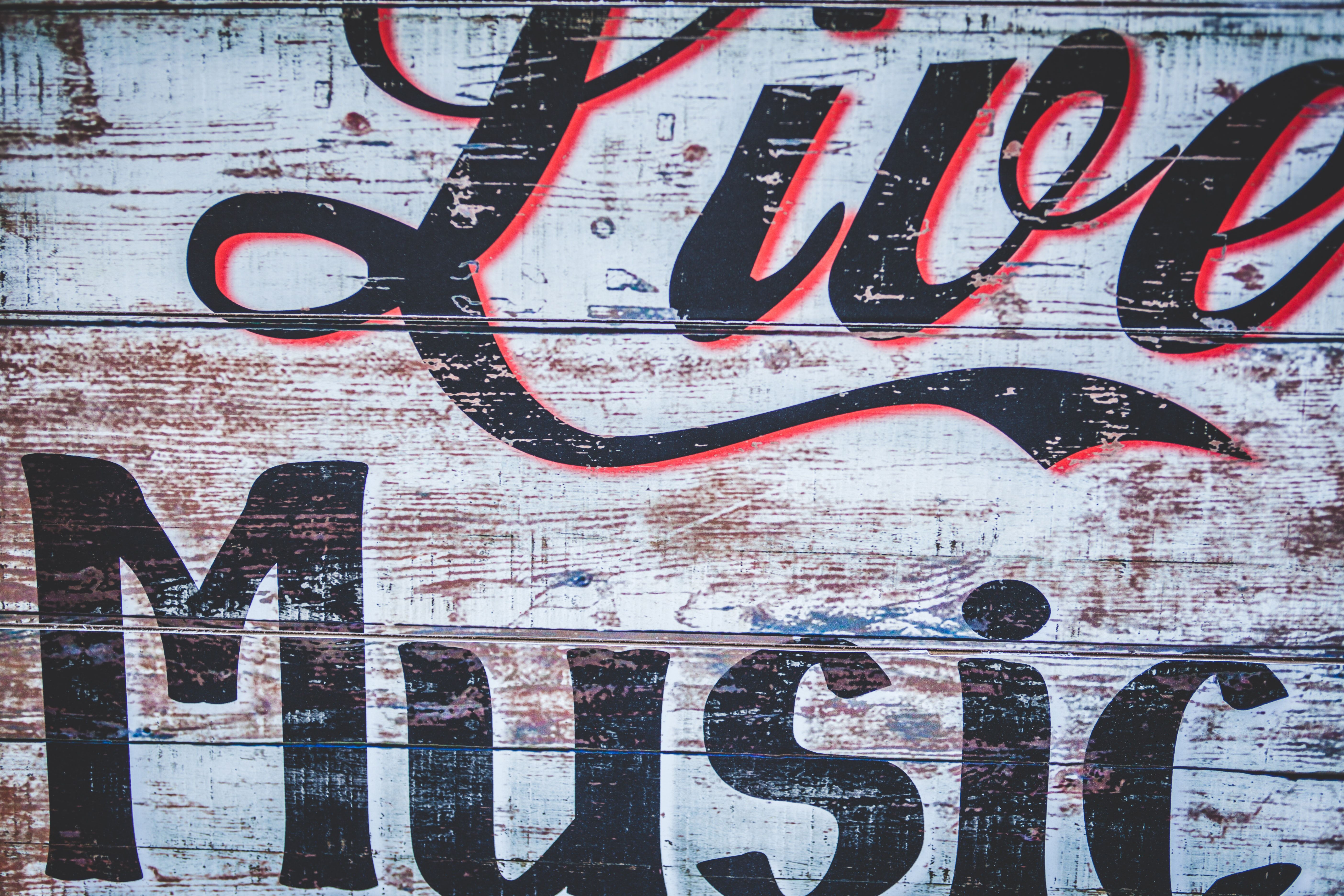 Courtesy of clem-onojeghuo from unsplash Close up of weathered wood with the words live music painted on