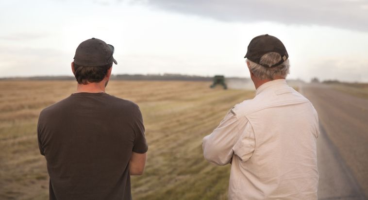 two farmers watching harvester