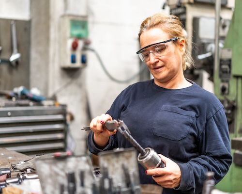 Female factory worker operator working in numerical control sector, industrial factory