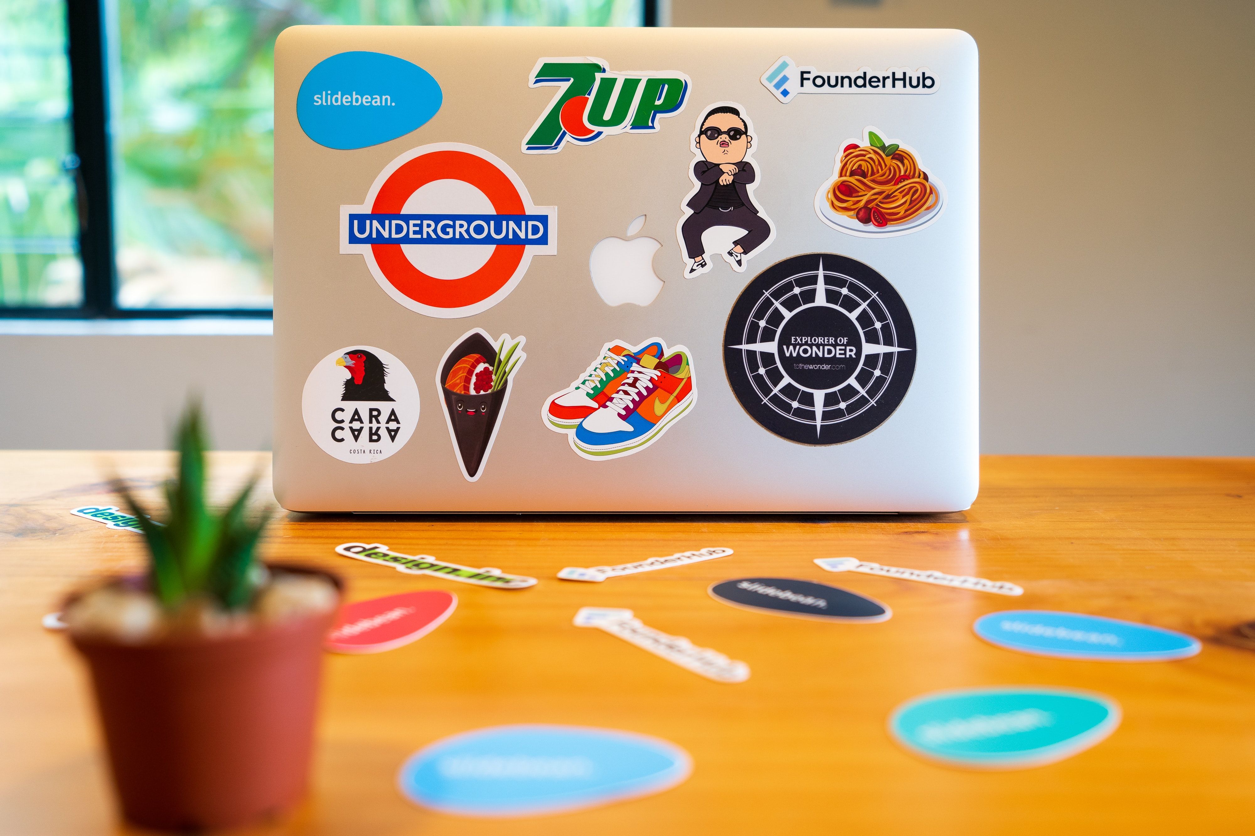 Courtesy of slidebean from unsplash Mac book with logo stickers on the back sitting on a wooden table.