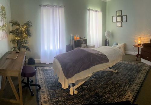 bright massage room with massage table, area rug, furniture