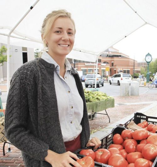 Midwife Grace at farmers market standing next to tomotatoes