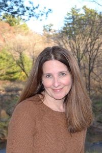 author Rebecca Mullin in brown sweater in front of nature scape