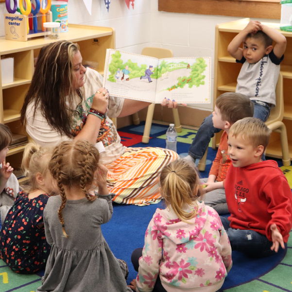 Children sitting in a circle being read a story