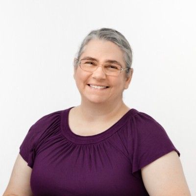 Renee Houston LMT Headshot Headshot of Renee Houston wither head tilted slightly to the right, wearing a purple top and smiling