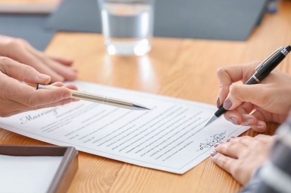 hands signing a letter with a black pen
