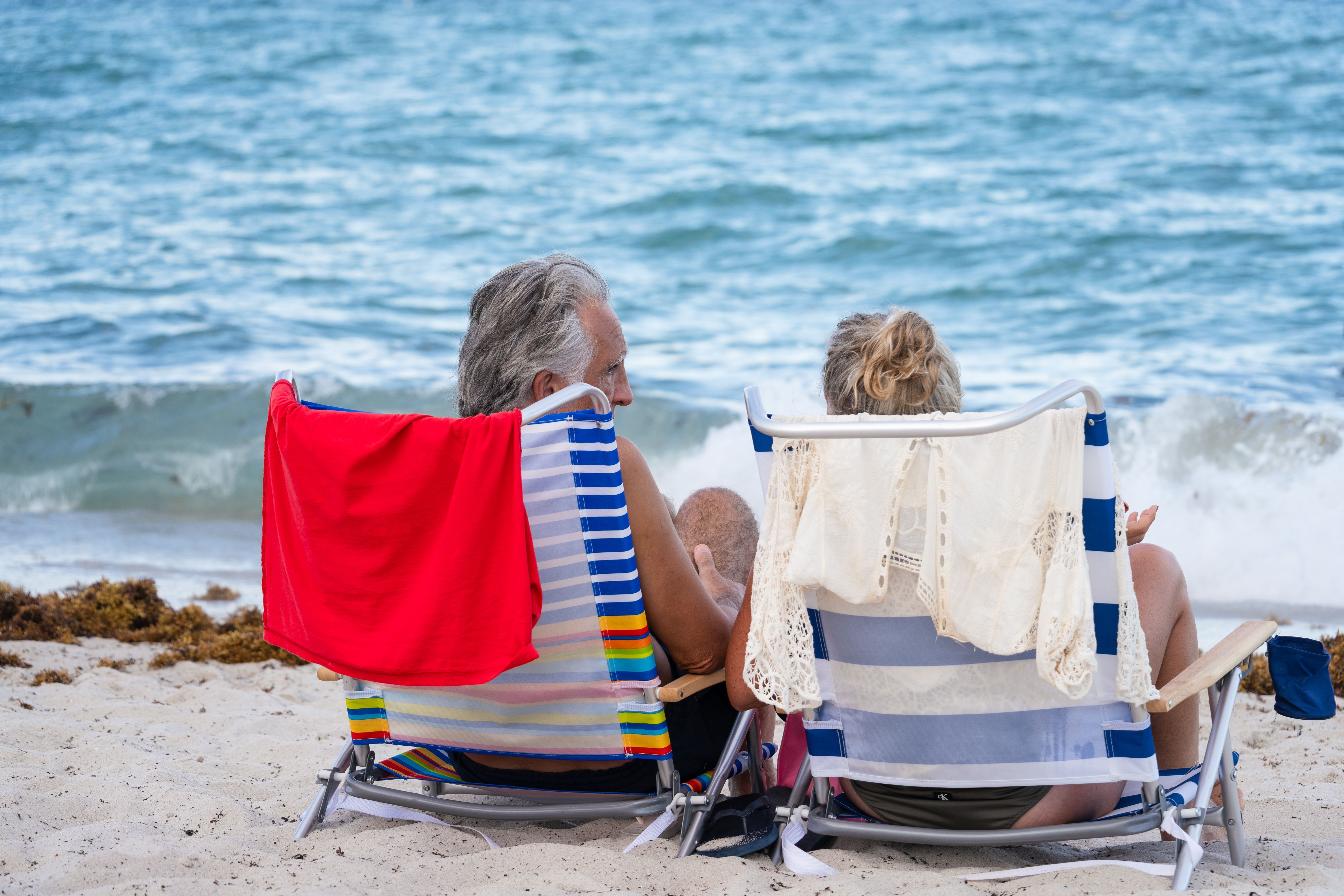 a couple sitting beach chairs facing the ocean