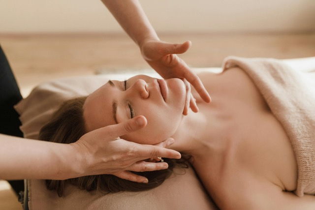 white woman on massage table covered by towel receiving massage