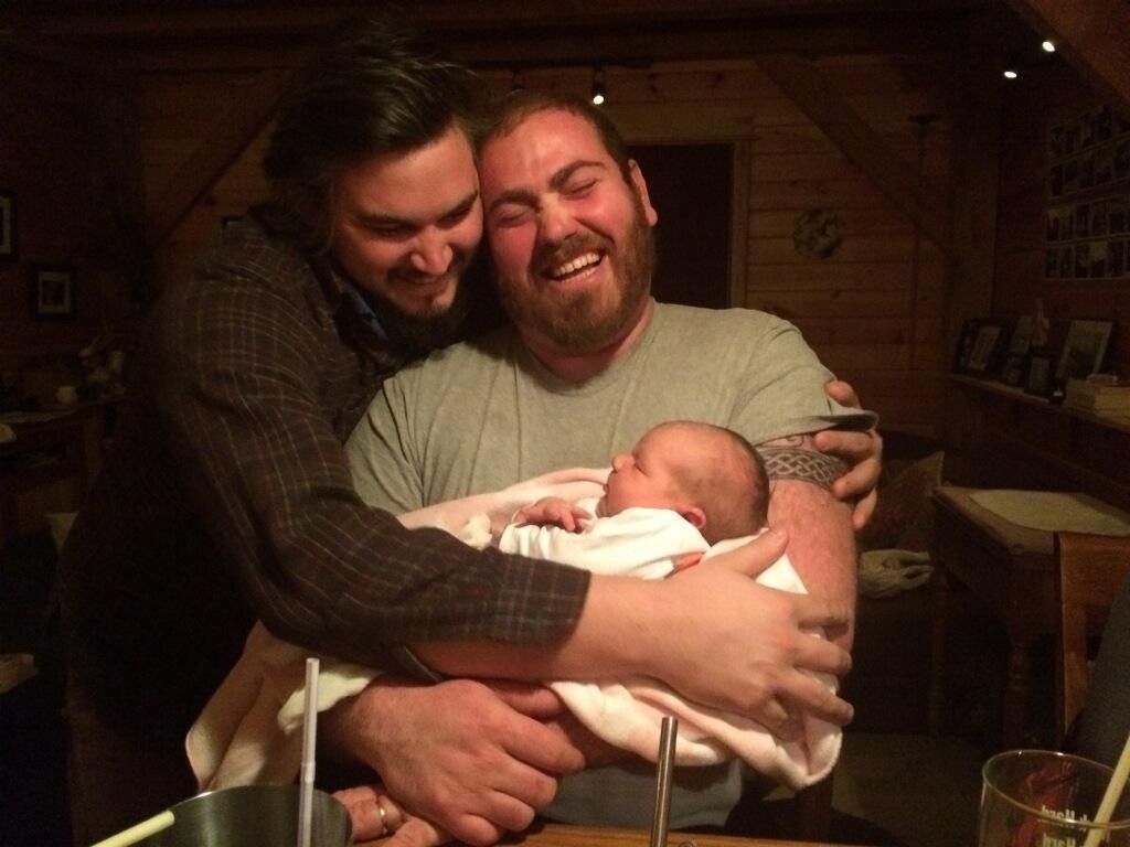 Two men, laughing holding baby