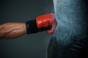 Hand of boxer and punching bag over black background