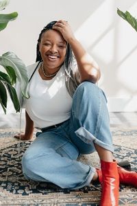 author Leah Johnson in a white shirt, jeans and red boots
