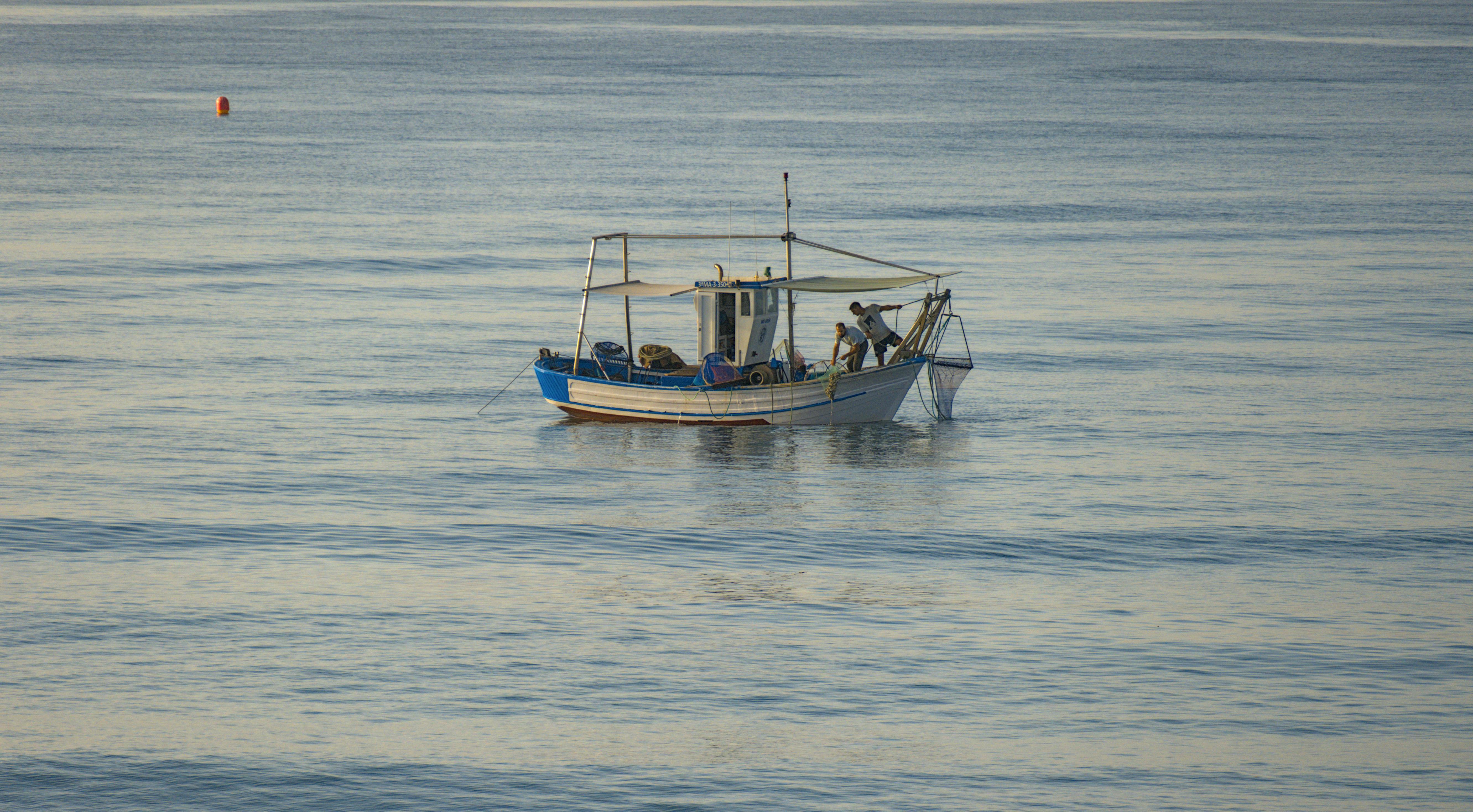 A traditional fishing boat with fishermen in calm Marbella waters at dawn.