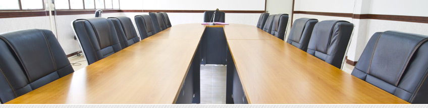 two parallel light wood rectangular meeting room tables surrounded by black executive style chairs