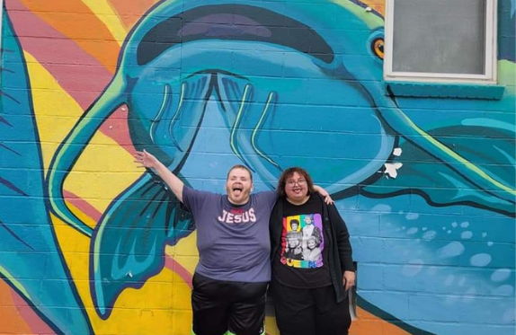 photo of Brad and Rita in front of a large fish mural
