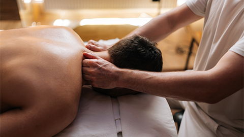 hands massading the neck of a prone massage client