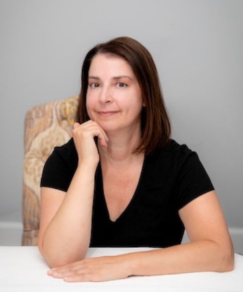 white woman with brown hair smiling towards camera