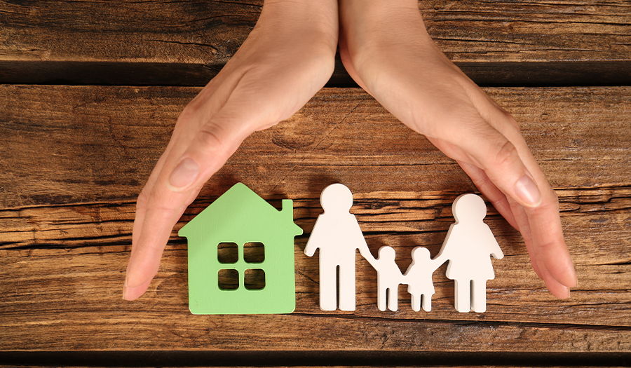 hands around paper cut out of family and house