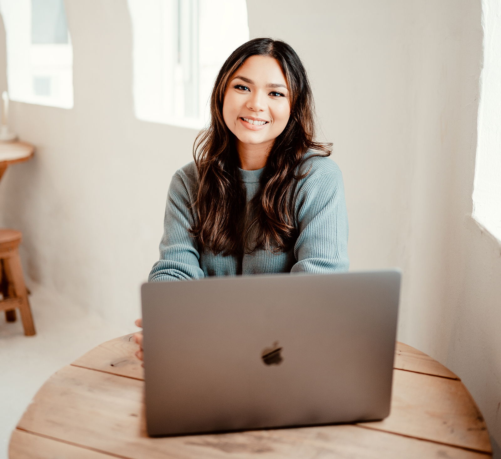 Stephanie Higgins sitting at a wooden table in front of laptop