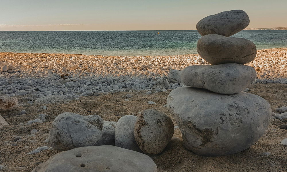 rocks are stacked up on a beach early in the morning. it is peaceul