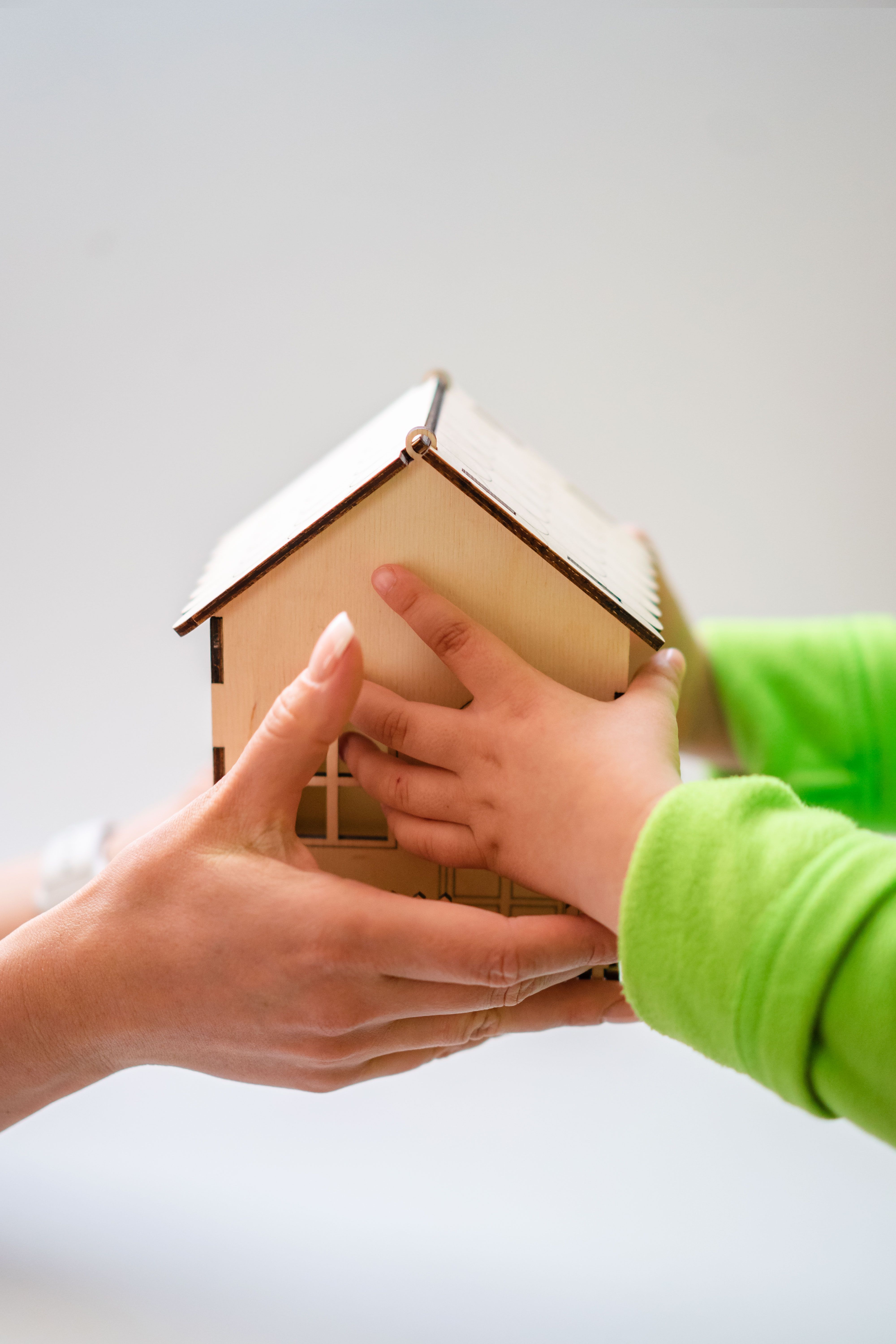 a model of a home being handed to a child by an adult