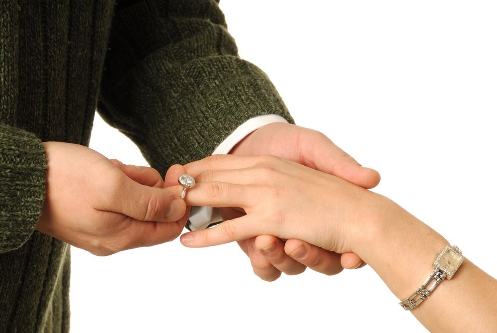 man putting ring on woman finger