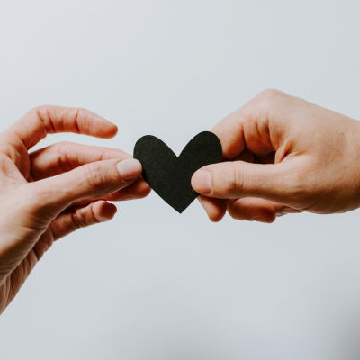 wellness scholarship fund 2 hands holding black heart shape paper