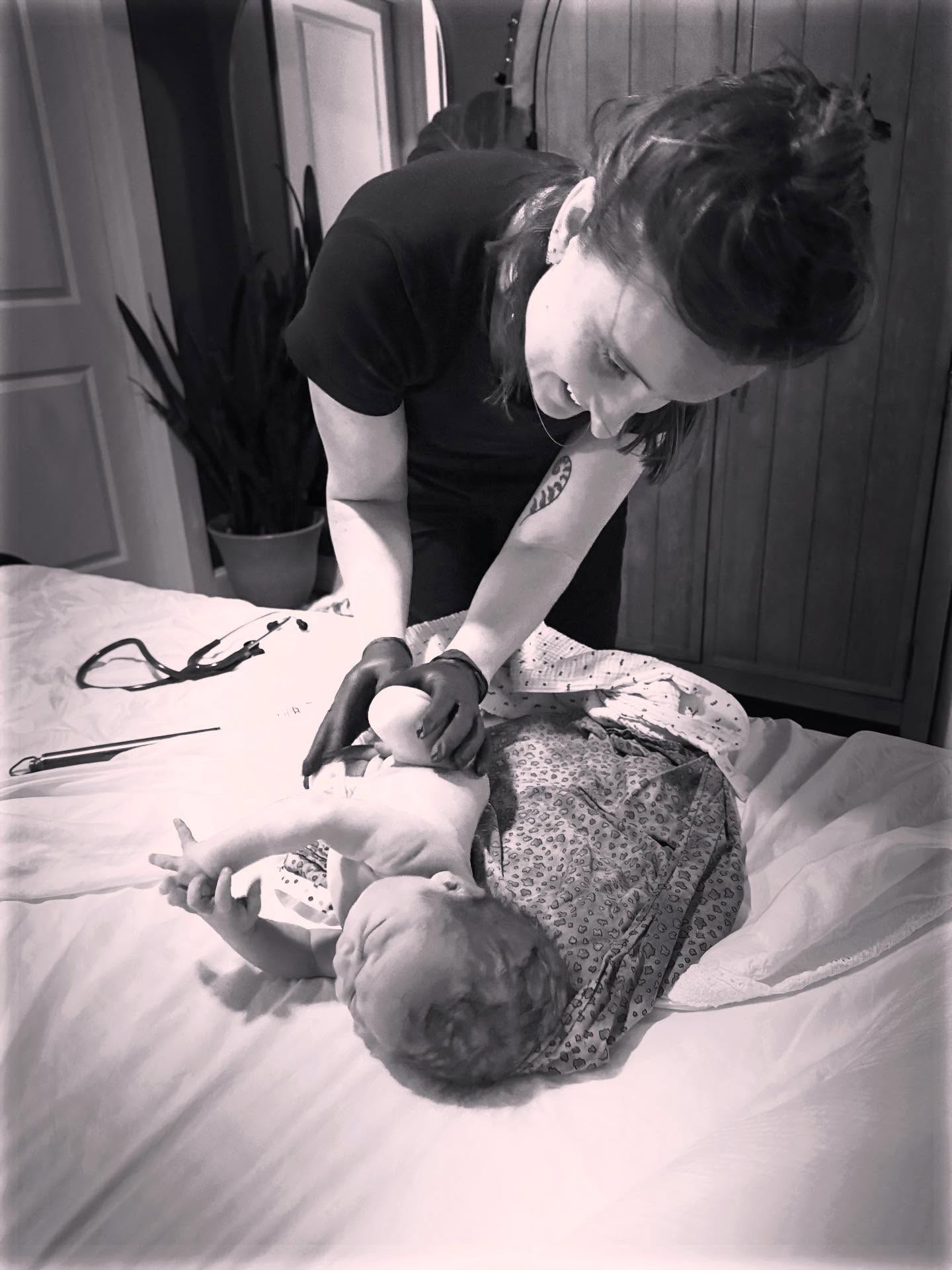 black and white image of midwife attending to newborn