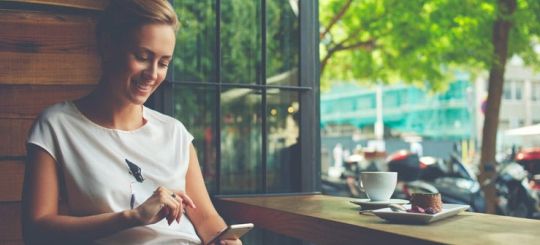 woman having coffee using phone