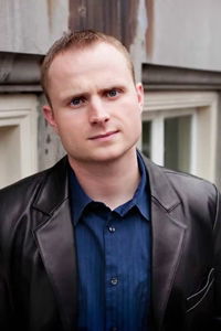 Author Michael Koryta in blue shirt and black leather jacket