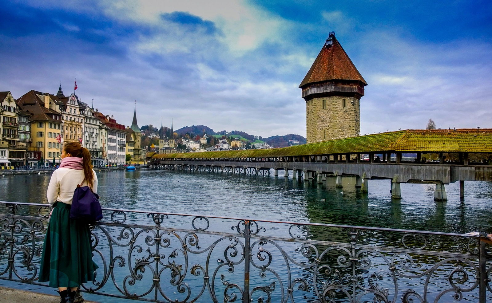 Woman leaning against railing in front of water in Switzerland city