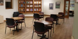 The Commons The Commons is a community spaces with small, round tables and padded chairs on a wood-patterned vinyl floor