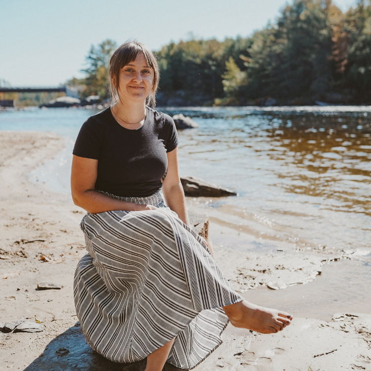 Midwife Danielle, sitting on rock next to river