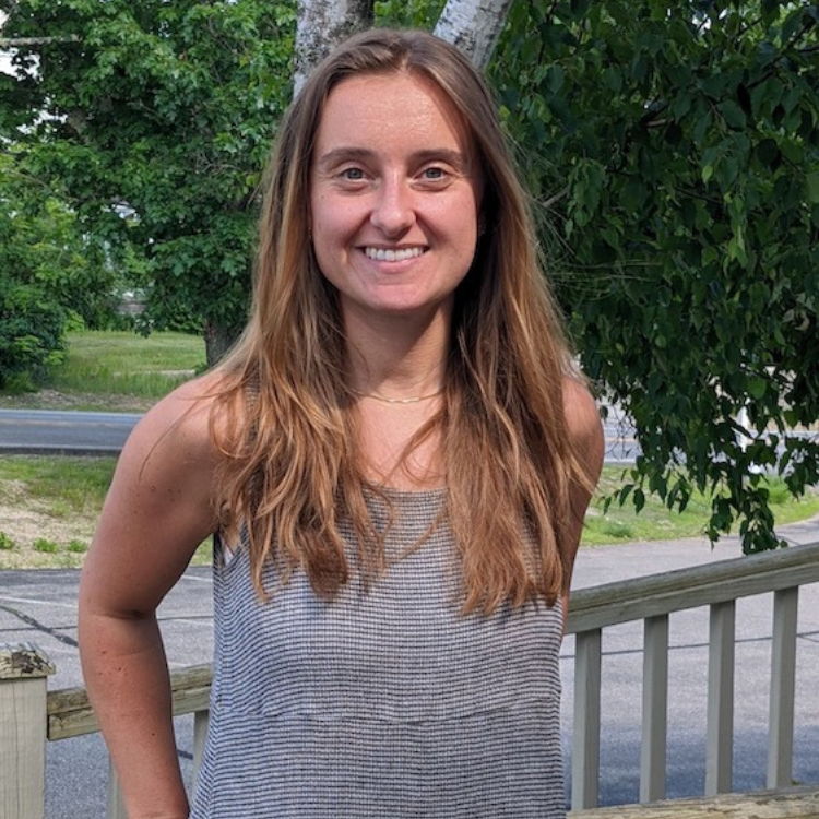 Young woman, smiling with long brown hair and gray tank top