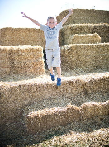 Explore Johnson County Agriculture child jumping off a hay bale