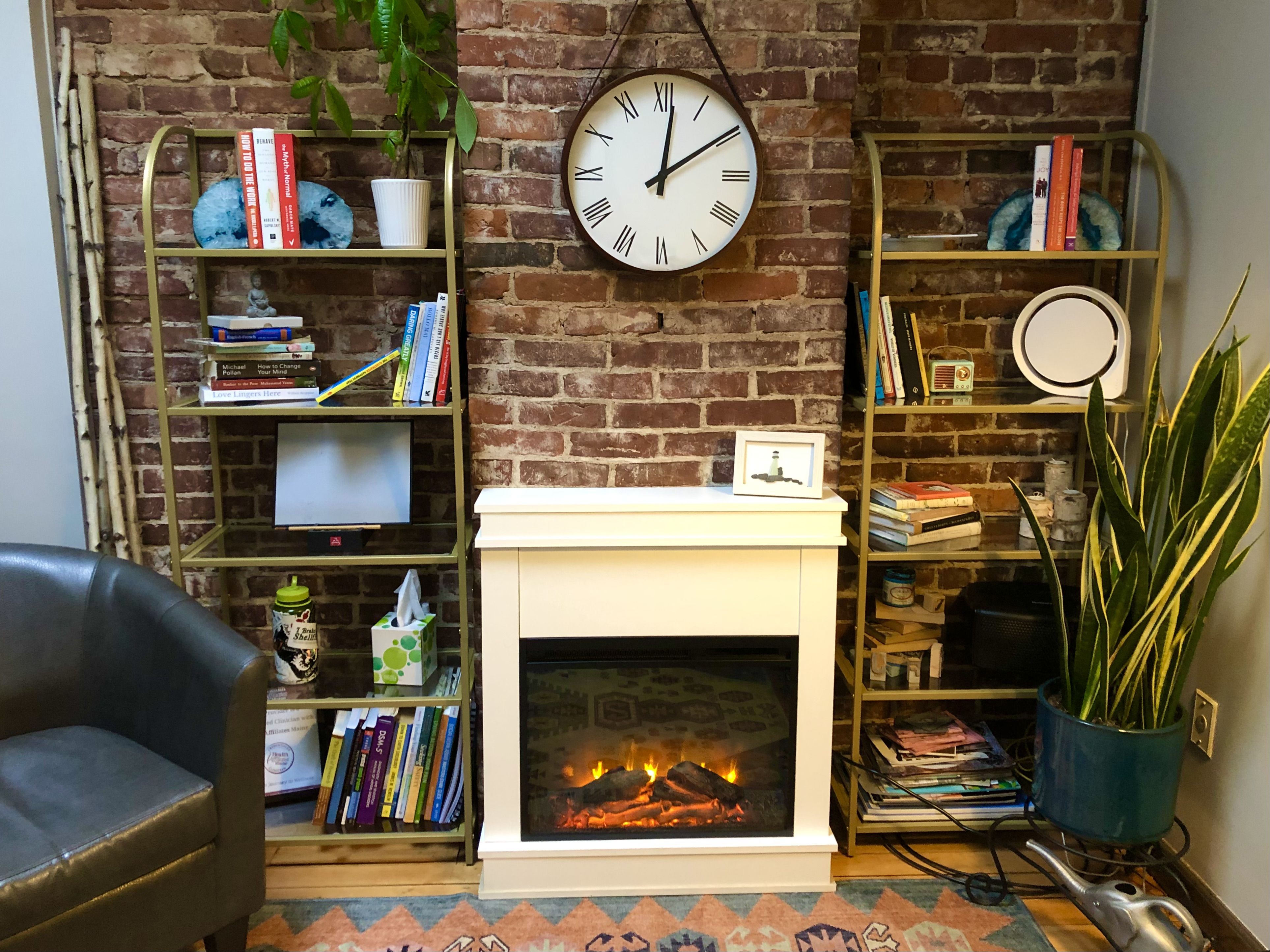 Fireplace by brick wall, book shelves and comfy chair