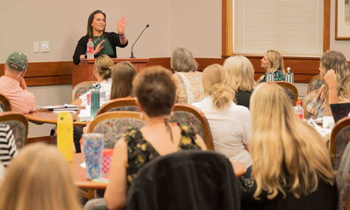 Woman standing at a podium in front of audience