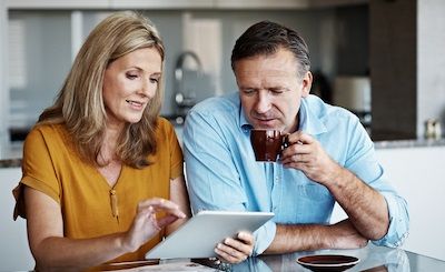 Couple in 50's reviewing tablet