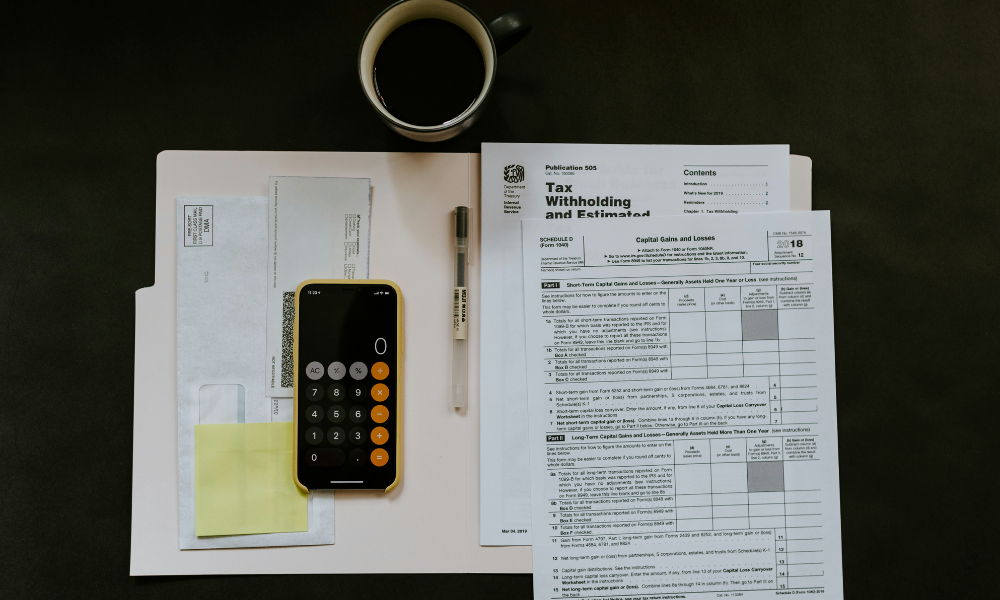 taxithholding a file with tax documents, a cup of coffee, and calculator on a desk