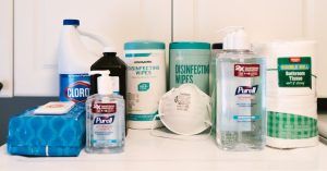 photo of bleach, sanitizing wipes, purell, a mask and paper towels