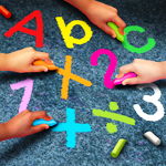 Children hands writing letters and numbers with sidewalk chalk Children hands writing letters and numbers with sidewalk chalk