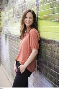 author Mary Kubica in peach shirt and black pants against brick wall