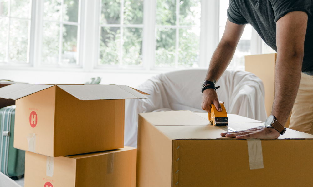 Packing boxes a person is moving out of their home. they are taping up moving boxes