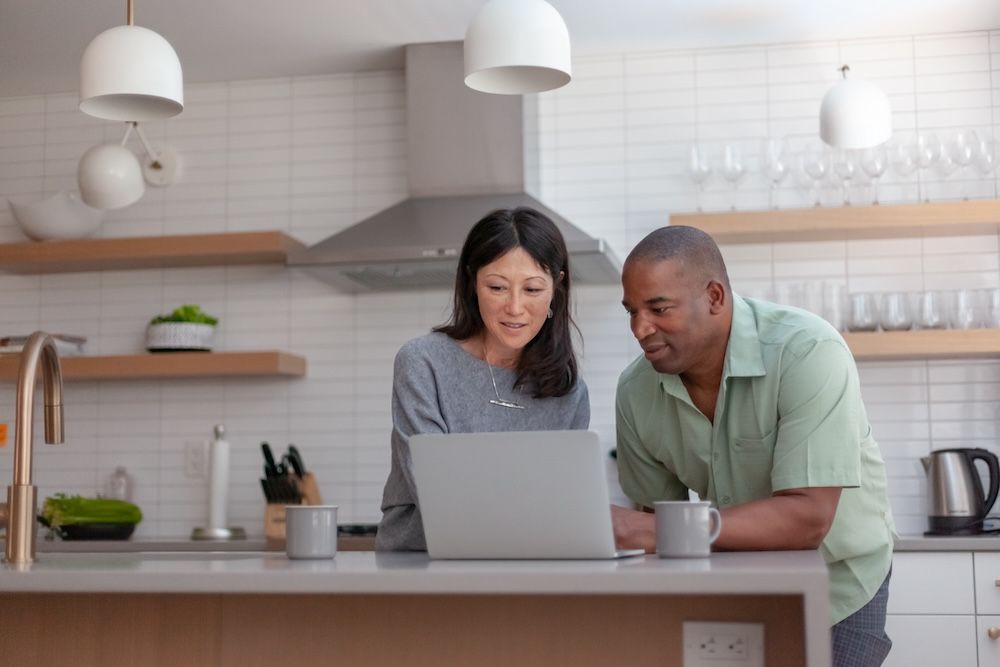 mixed race couple using computer on island in kitchen