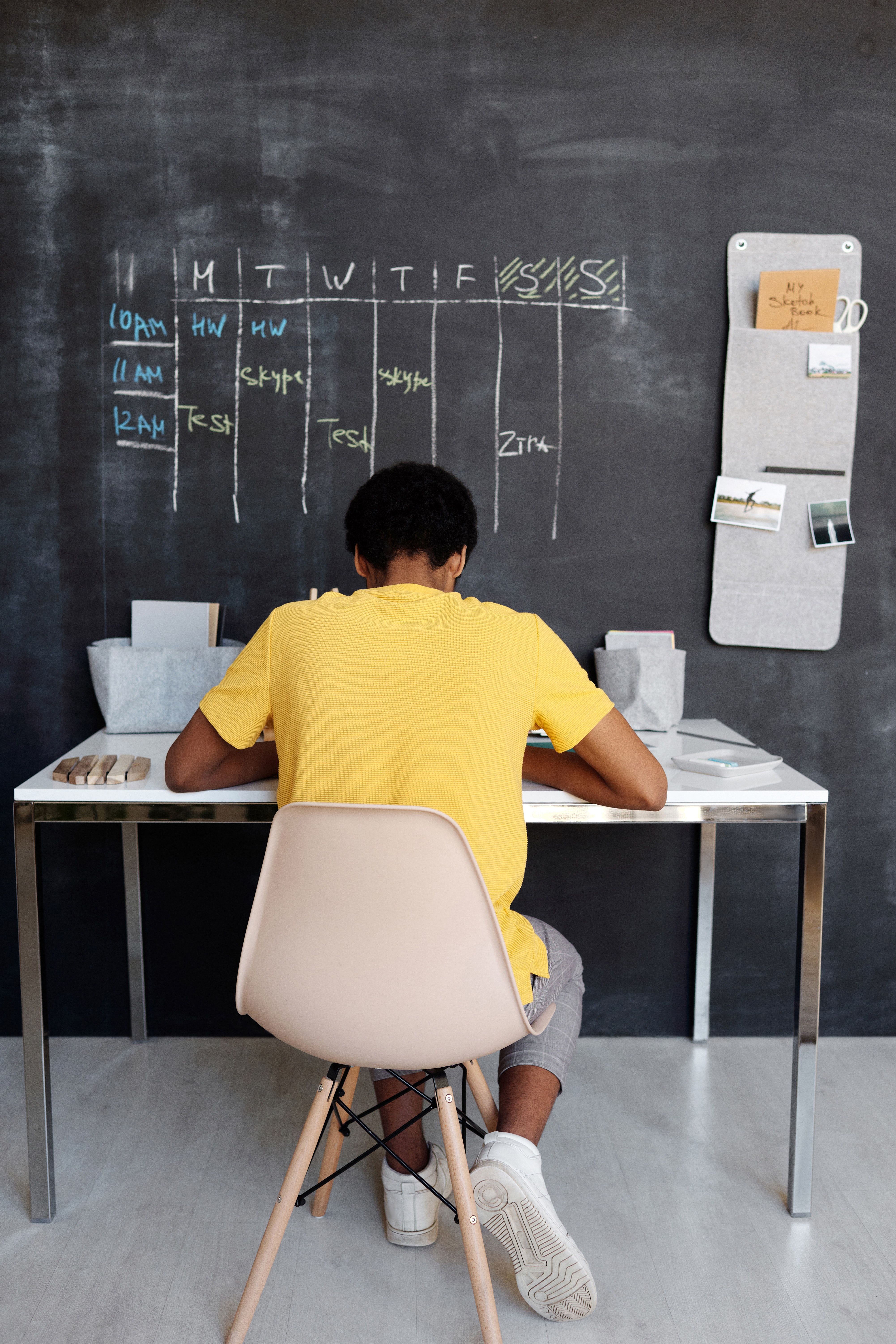Courtesy of julia-m-cameron from pexels Student sitting at a desk facing a large chalkboard wall with a calendar drawn on it